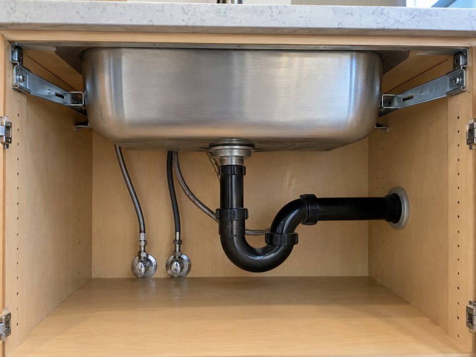 Hand Compact undermount workstation sink with a wooden cutting board resting on intCompact undermount workstation sink with a wooden cutting board resting on internal ledgesernal ledgeswiping bread crumbs from the countertop toward a stainless steel undermount sink